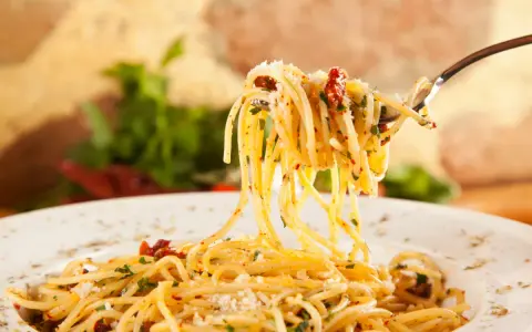 Widok z bliska na widelec z porcją spaghetti, posypane parmezanem i ziołami. Idealne jakie przyprawy do spaghetti!