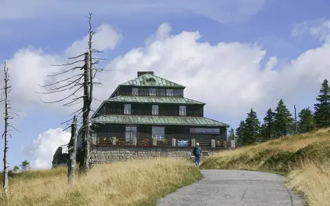 Schronisko Odrodzenie w Karkonoszach, z charakterystyczną architekturą i otoczone suchymi drzewami.