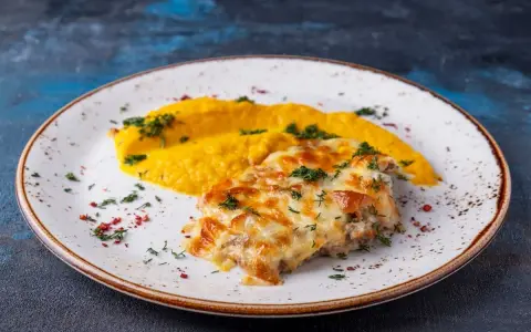 Schab po zbójnicku z purée z dyni, posypany zieloną pietruszką i czerwonym pieprzem.