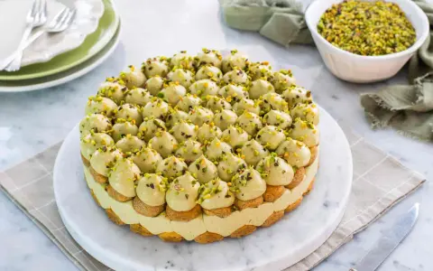 Torta rotonda con tante piccole meringhe verdi e granella di pistacchio, un delizioso tiramisù al pistacchio.
