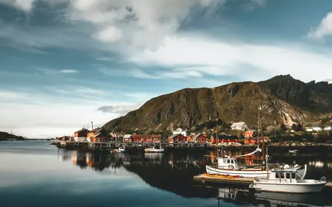 Malowniczy norweski port z czerwonymi domkami i łodziami. Czy do Norwegii trzeba mieć paszport? Sprawdź przed podróżą!
