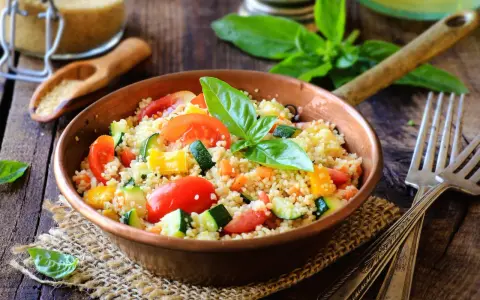 Un piatto colorato con couscous, pomodori, zucchine e peperoni, perfetto per una ricetta cous cous originale e fresca.