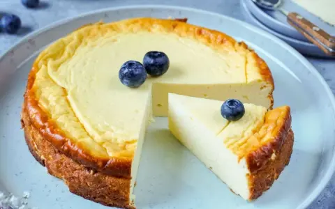 Ein köstlicher low carb Kuchen mit Blaubeeren, der auf einem Teller serviert wird. Ein Stück ist bereits herausgeschnitten.