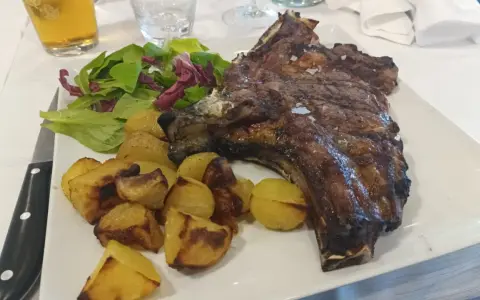 Succulenta costata di manzo alla griglia, servita con patate arrosto croccanti e un'insalata fresca. Un piatto da vero intenditore.