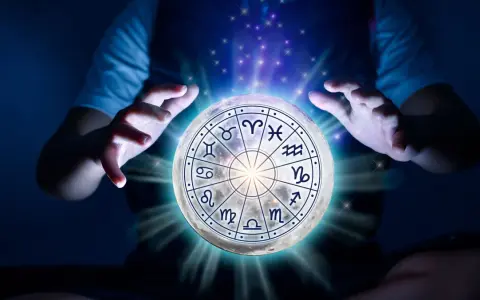 Dłonie unoszą księżyc z tarczą zodiaku, gdzie znaki zodiaku i żywioły splatają się w mistycznym świetle.