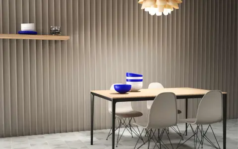 Paredes acanaladas que disimulan imperfecciones, mesa de comedor con sillas modernas y un estante con decoración.