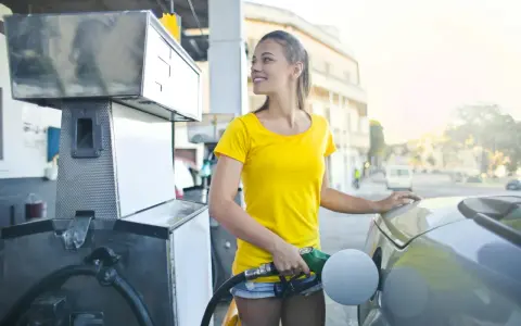 Uśmiechnięta dziewczyna tankuje auto, nalewając Vervę 98.