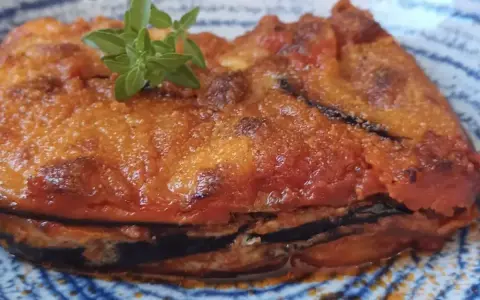 Parmigiana in padella, uno strato di melanzane fritte, pomodoro e formaggio, guarnita con basilico fresco.