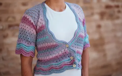Chaqueta de crochet con rayas degradadas en tonos pastel y delicados puntos calados. Tres botones de madera cierran la prenda.