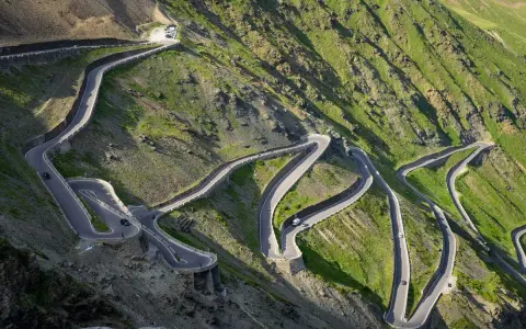 Strada tortuosa che sale verso il passo più alto d'Europa, con tornanti stretti e panorami mozzafiato.