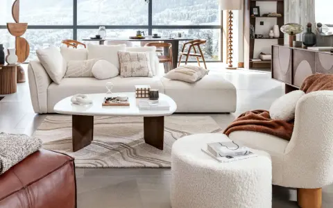 Un confortable salon d'hiver avec un canapé moelleux, une table basse design et une vue panoramique sur les montagnes enneigées.