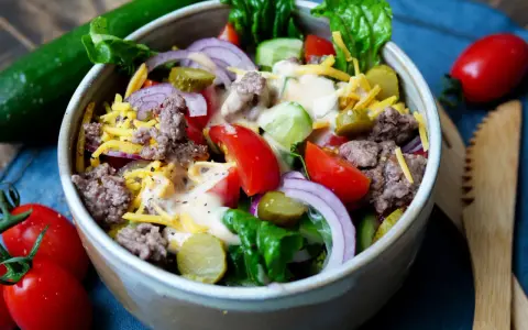 Schmackhafter Big Mac Salat mit Hackfleisch, Käse, Gurken, Tomaten und Zwiebeln, beträufelt mit einer cremigen Sauce.