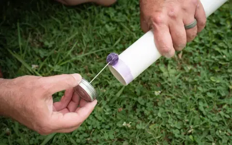 Przygotowanie do klejenia rur PVC. Ręka trzyma puszkę z klejem, a druga ręka przygotowuje rurę.