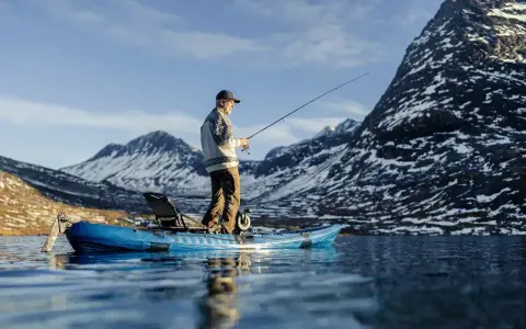 Man fiskar från en kajak i en fjällsjö. Frågan är hur långt paddlar man på en dag i sådan vacker natur?