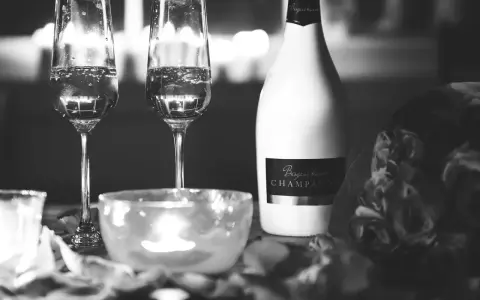 Deux flûtes de champagne pétillant, une bouteille de "Besgane bianc CHAMPAGNE" et des roses, ambiance romantique.