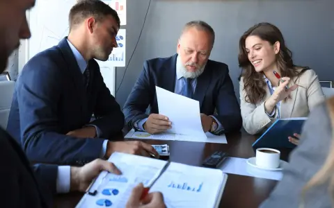 Team discusses broker-dealer compliance, reviewing charts and documents in a meeting.