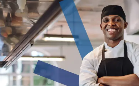 Chef sonriente en cocina profesional, ideal para la seleccion personal hosteleria.