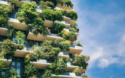Ein Hochhaus, das wie ein vertikaler Garten aussieht. Bäume und Pflanzen wachsen auf den Balkonen und Fassaden. Ein Beispiel für klimagerechtes Bauen.