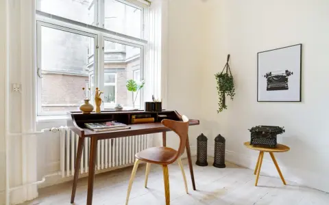 Ett elegant skrivbord i oljad ek med en läderklädd stol. En gammal skrivmaskin står på ett litet sidobord.