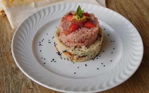 Due torri di riso, una rosa con fragole e menta, l'altra bianca con verdure e semi neri. Un piatto che ricorda la crema di riso.