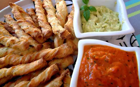 Chrupiące paluszki grissini z ziołami, idealne do podania z kremowym guacamole i pikantnym sosem pomidorowym.