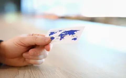 Dłoń trzyma kartę z mapą świata.
