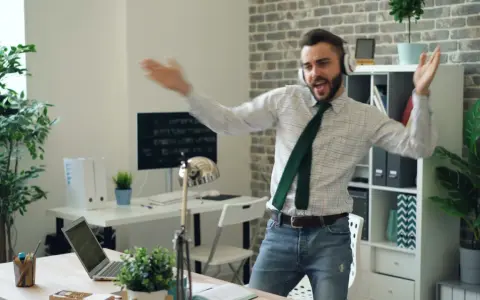 Mężczyzna z **ENFP osobowością** tańczy w biurze, słuchając muzyki na słuchawkach.