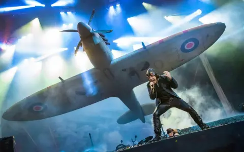 Bruce Dickinson sjunger framför ett Spitfire-plan under Iron Maiden Ullevi. Scenen är fylld av rök och ljus.