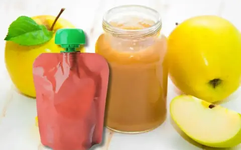 Jabłkowe puree w słoiczku i saszetce, idealne jako soki dla niemowląt od 3 miesiąca. Obok świeże jabłka.