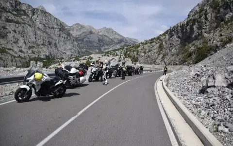 Grupa motocyklistów zatrzymała się na malowniczej drodze w Albanii, podziwiając spektakularne widoki gór.