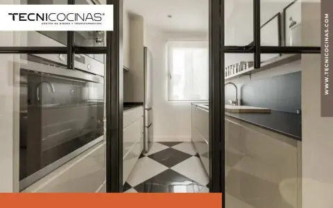 Cocina semiabierta cristal con suelo de damero, electrodomésticos integrados y encimera moderna.