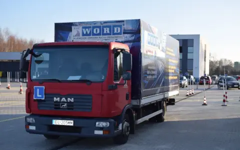 Czerwona ciężarówka MAN z literą "L" na masce i logo WORD. Na naczepie widnieje napis "WOJEWÓDZKI OŚRODEK RUCHU DROGOWEGO". To miejsce, gdzie składa się wniosek PKZ.