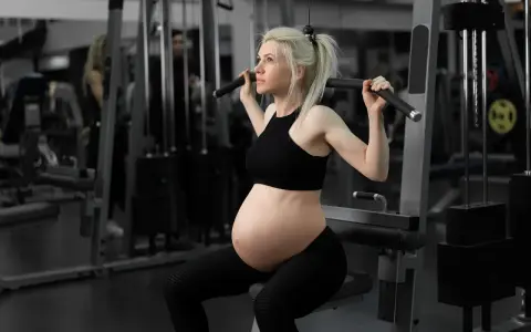 Gravid kvinna tränar marklyft i gym.