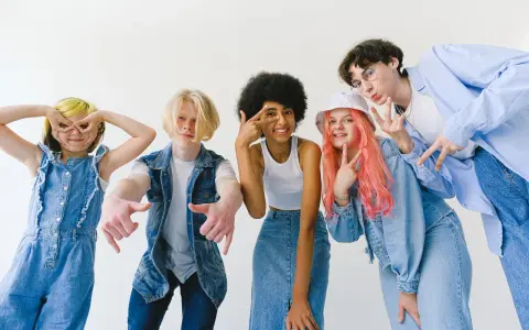 Ragazzi con un look anni '90, tutti vestiti di jeans, fanno pose divertenti.