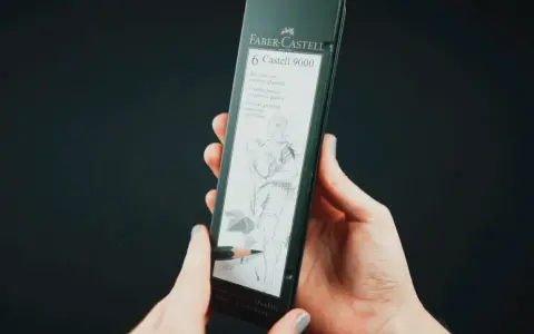 Dłonie trzymają opakowanie z sześcioma ołówkami Faber-Castell 9000. Jeden ołówek rysuje szkic postaci.