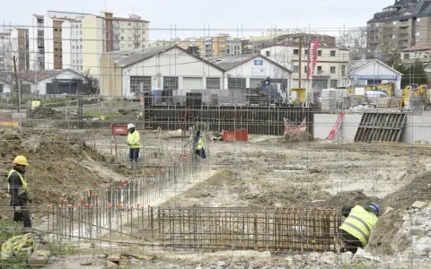 Obreros trabajan en la preparación de cimientos para nuevos proyectos de construcción. Se ven varillas de acero y maquinaria pesada en un día nublado.