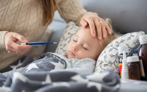 Matka mierzy gorączkę śpiącemu dziecku, troskliwa opieka nad zdrowym dzieckiem, gdy jest chore.