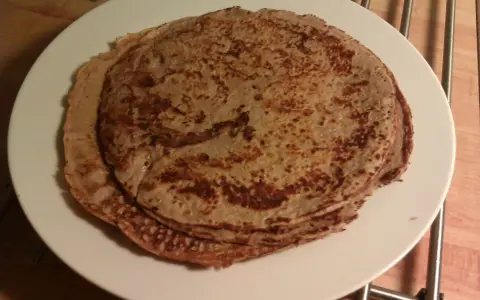 En hög med tunna pannkakor på en vit tallrik. Perfekt för en mysig frukost eller som frukost tips.
