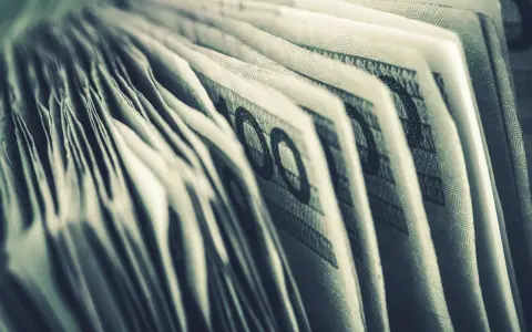 Zbliżenie na banknoty 100 zł. Widoczne detale i wzory, sugerujące zgromadzone środki, być może jako konto depozytowe osadzonego.