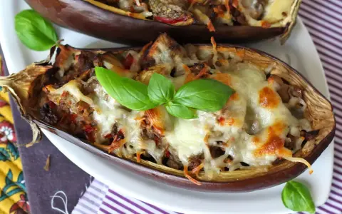Melanzane ripiene al forno velocissime, dorate e filanti, guarnite con basilico fresco. Un piatto invitante e facile da preparare.