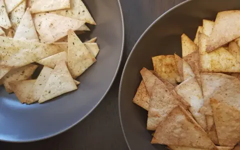 Dwa talerze pełne chrupiących chipsów z tortilli, jedne z ziołami, drugie z przyprawami. Idealne na imprezę!