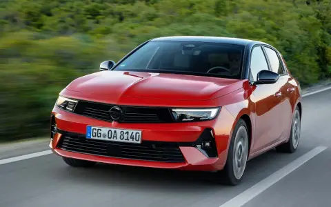 El nuevo Opel Astra rojo, con techo negro, circula por una carretera sinuosa rodeada de vegetación.