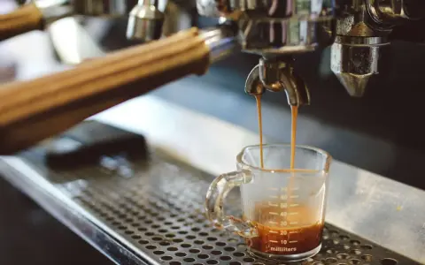 Espresso spływa do szklaneczki. Czy ekspres do kawy pobiera dużo prądu? To zależy od modelu, ale ten wygląda na profesjonalny.