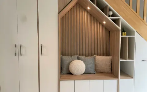 Aménagement cage d'escalier avec banquette confortable, coussins douillets et rangements intégrés.