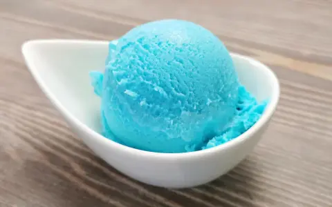 Ein Löffel leuchtend blaues Kaugummi Eis in einer weißen Schale. Perfekt für ein selbstgemachtes Kaugummi Eis Rezept.