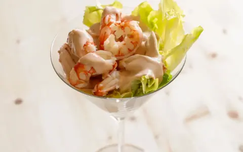 Gamberetti in salsa rosa, un antipasto fresco e gustoso servito in una coppa, con foglie di lattuga croccante.