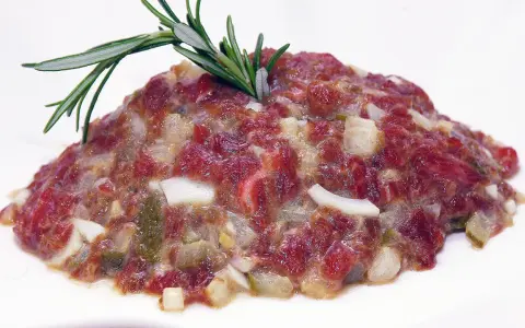 Delicioso steak tartar de los Hermanos Torres, con carne picada, cebolla, pepinillos y un toque de romero.