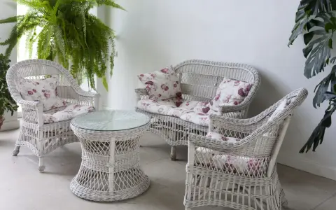 Conjunto de muebles de mimbre blanco con cojines florales, ideal para restaurar muebles de mimbre y darles un toque fresco.