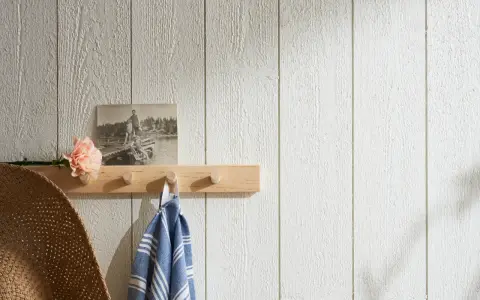 En träpanel inomhus inspiration med en ljus trähylla, en gammal bild, en blomma och en handduk.