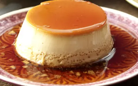 Delicioso flan de café con caramelo líquido, servido en un plato con un diseño intrincado.
